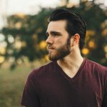 man wearing maroon v-neck t-shirt in forest