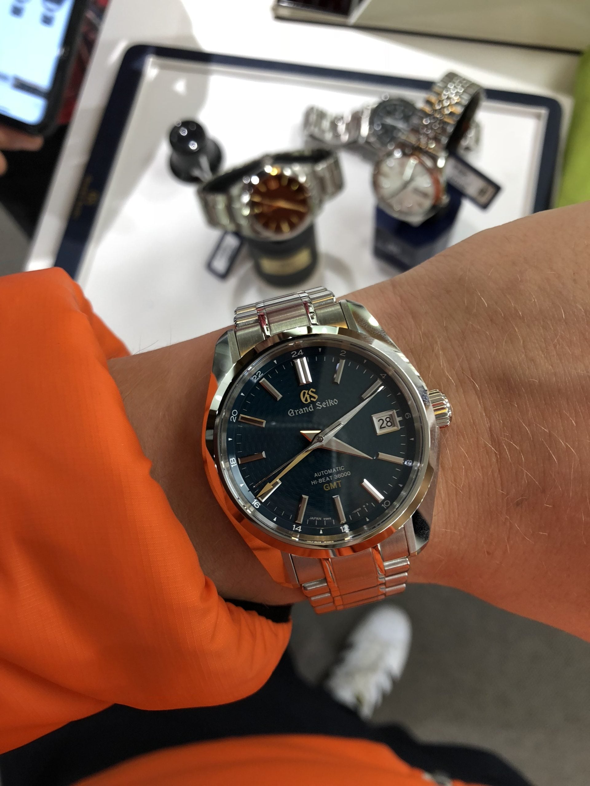 grand seiko hi-beat 36000 gmt (sbgj227) med blå texturerad tavla, guldfärgad gmt-visare, datum och stållänk – hands-on på handleden