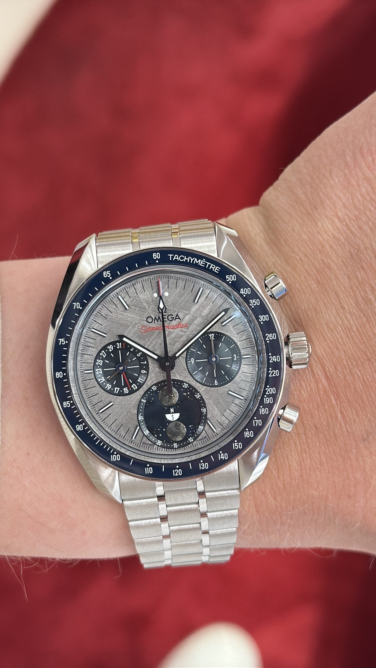 omega speedmaster moonphase med grå meteorittavla, månfas och blå tachymeterlünett på stållänk – hands-on