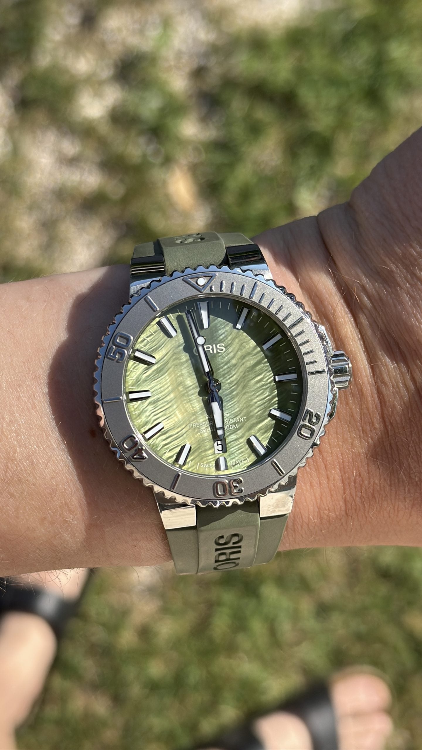 oris aquis date med grön texturerad pärlemortavla, grå lünett och grön gummirem – hands-on på handleden