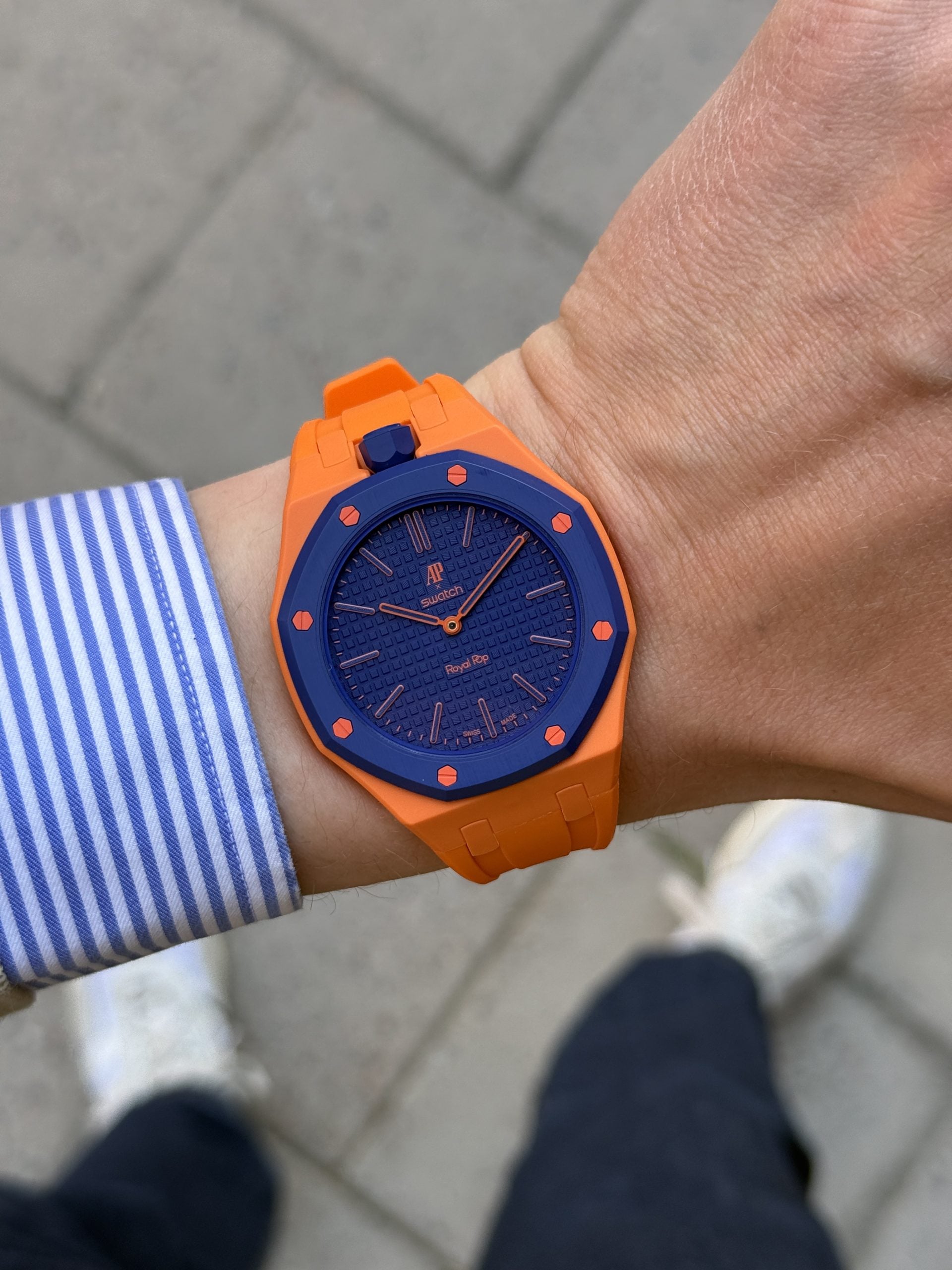 Ap × swatch royal pop orenji hachi med orange boett och blå tavla, buren på handleden med orange gummistrap ap × swatch royal pop orenji hachi med orange boett och blå tavla, buren på handleden med orange gummistrap