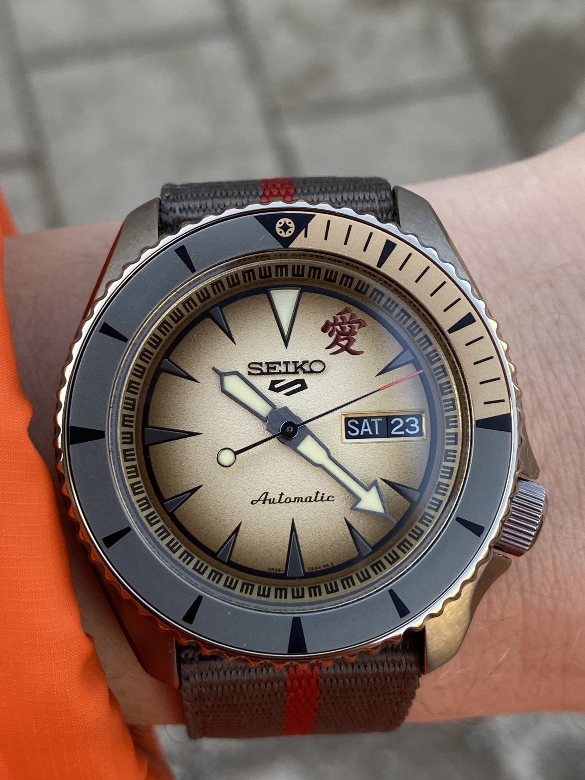 seiko 5 sports naruto & boruto limited edition (gaara, srpf71) med sandbeige tavla, rött kanji, grå-guld lünett och brun seatbelt-nato – hands-on på handleden