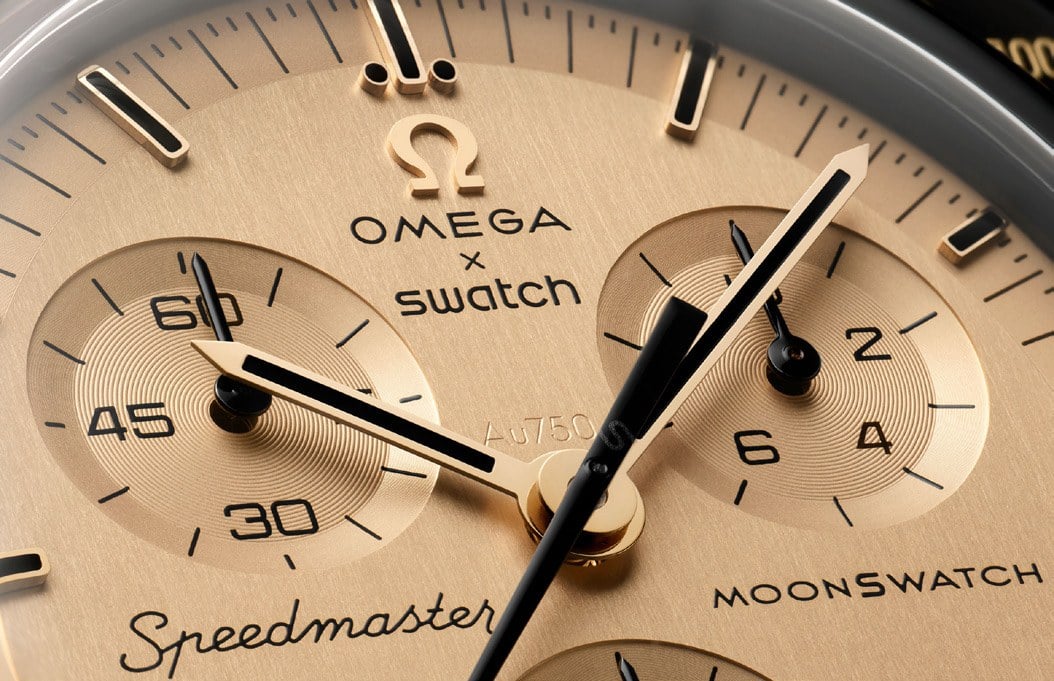 urtavla i guld på omega x swatch mission to the moon 1969 med speedmaster-logotyp och au750-stämpel
