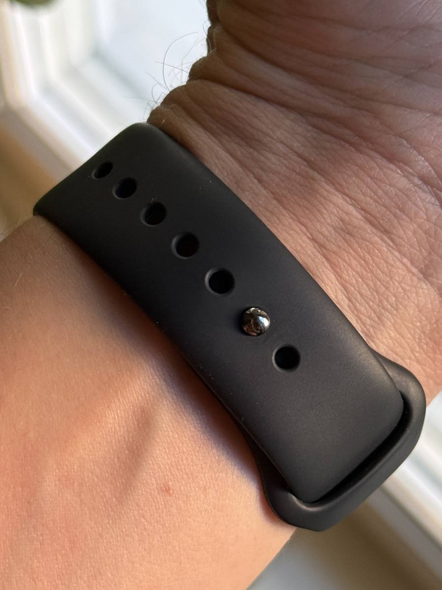 undersidan av ett svart sportband på handleden där metallknappen sitter genom ett av justeringshålen