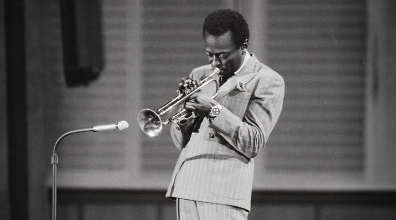 miles davis i randig kostym spelar trumpet med sin breitling navitimer ref. 806 mk5 på handleden