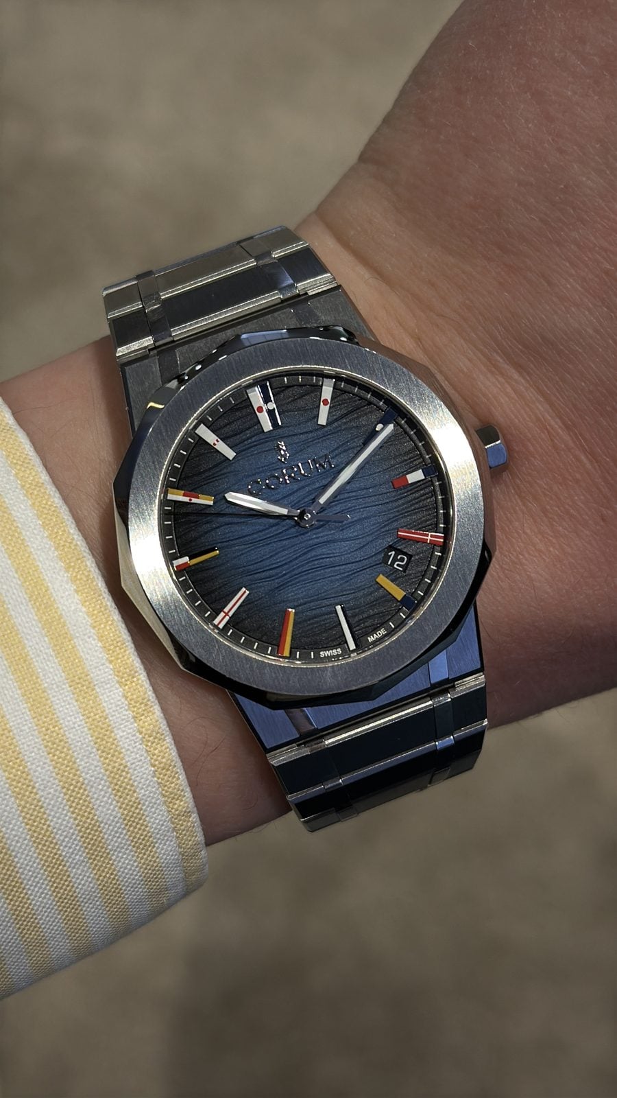 Corum admiral 39 i stål med mörkblå strukturerad urtavla och nautiska signalflaggor på handleden under watches and wonders 2026 corum admiral 39 i stål med mörkblå strukturerad urtavla och nautiska signalflaggor på handleden under watches and wonders 2026