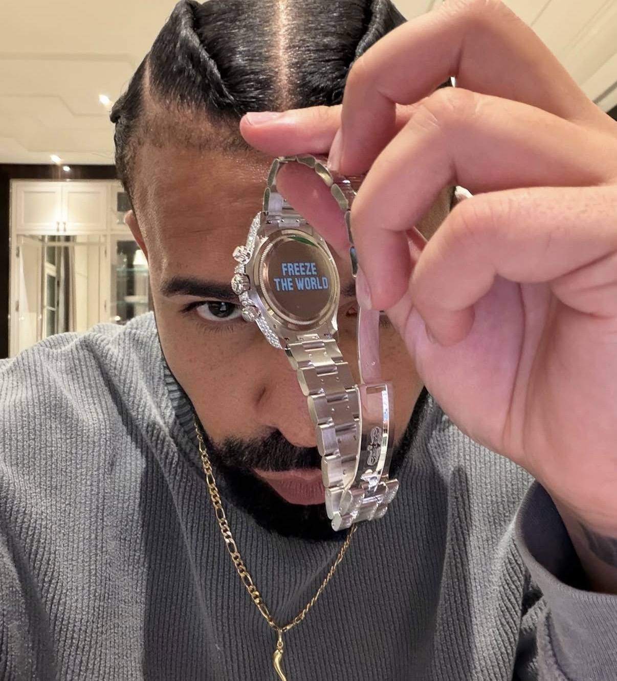 drake håller upp boettlocket på sin rolex daytona med graveringen freeze the world