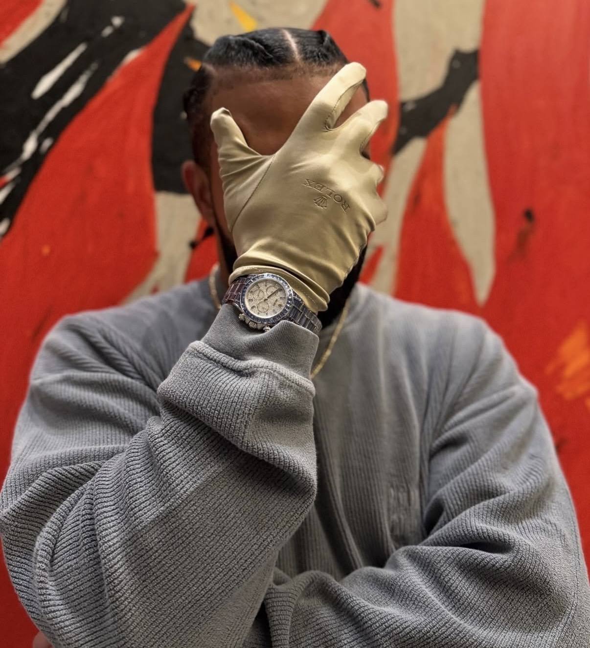 drake bär sin ice gradient daytona och håller upp en handske med rolex-logotyp