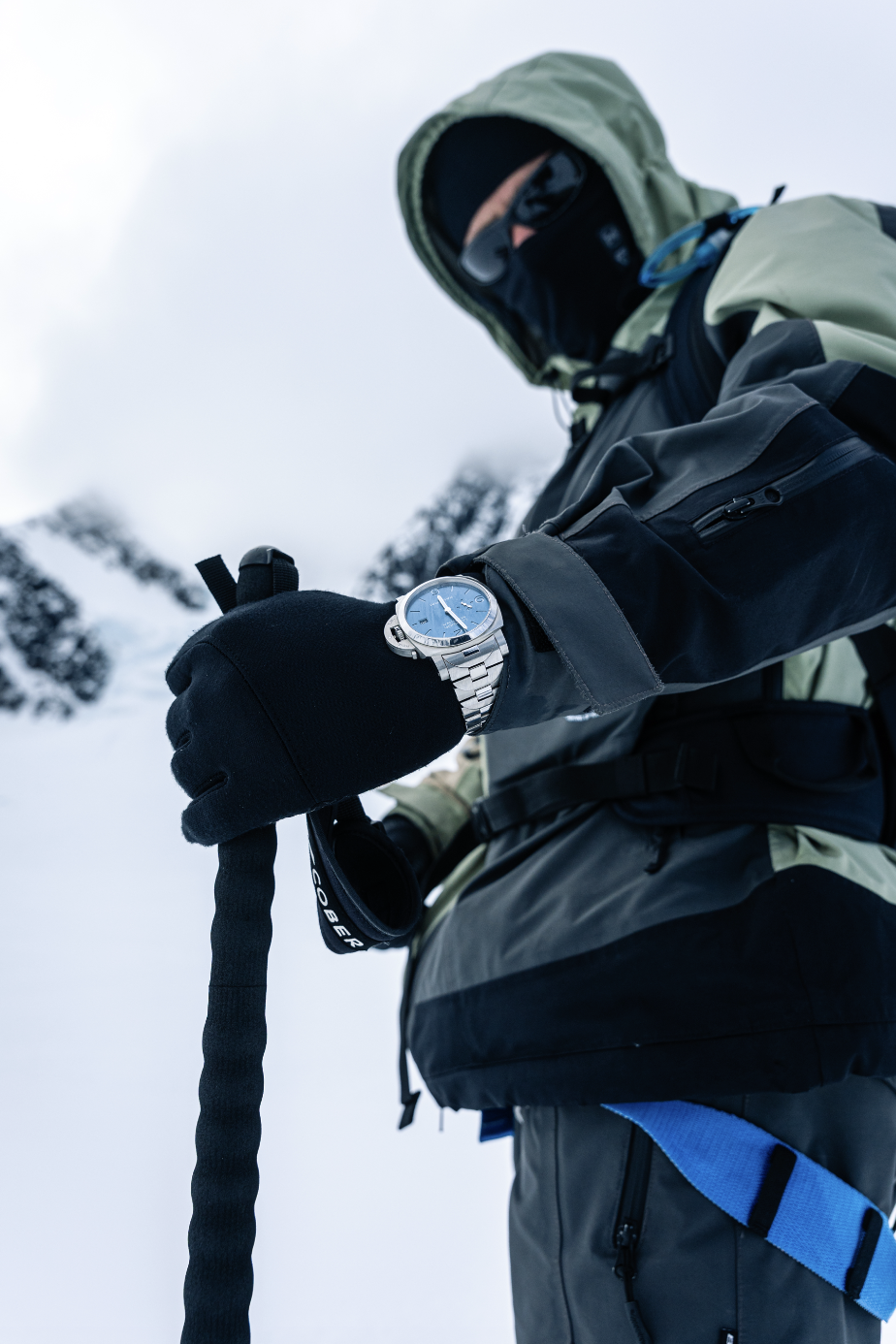 Côme girardot i skalplagg och balaklava kollar sin panerai med ljusblå urtavla i snölandskap côme girardot i skalplagg och balaklava kollar sin panerai med ljusblå urtavla i snölandskap
