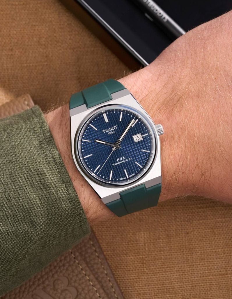 tissot prx med blå urtavla och grönt gummiarmband på handleden