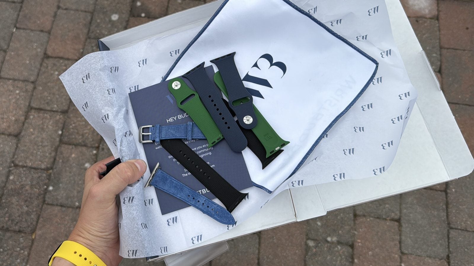 wristbuddys leveranskartong öppnad med silkespapper, mikrofiberpåse och sex armband till apple watch