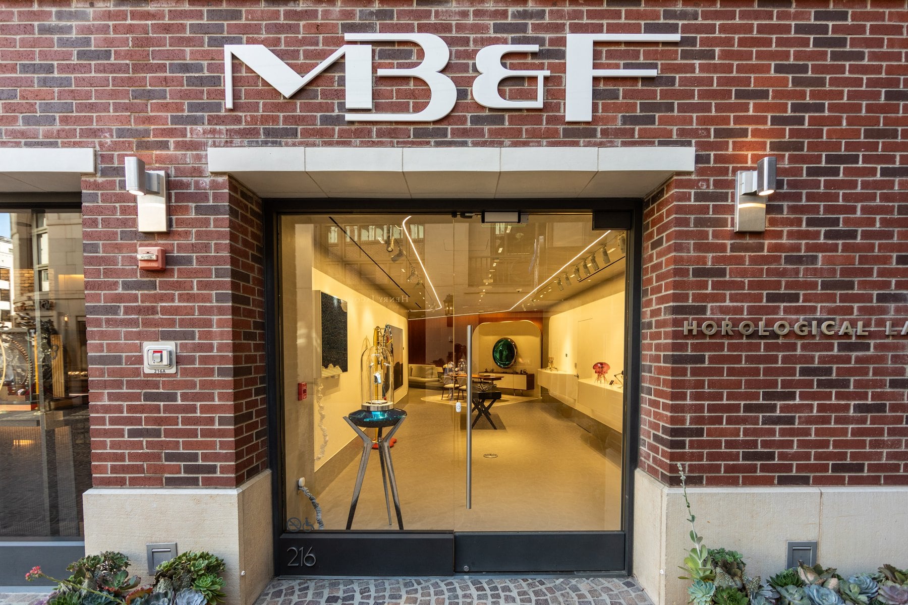utställningsvägg med samtliga tretton mb&f horological machines i upplysta montrar