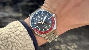 spinnaker dumas gmt automatic cobalt crimson på handleden i dagsljus, med blå och röd 24-timmarsbezel och stålarmband