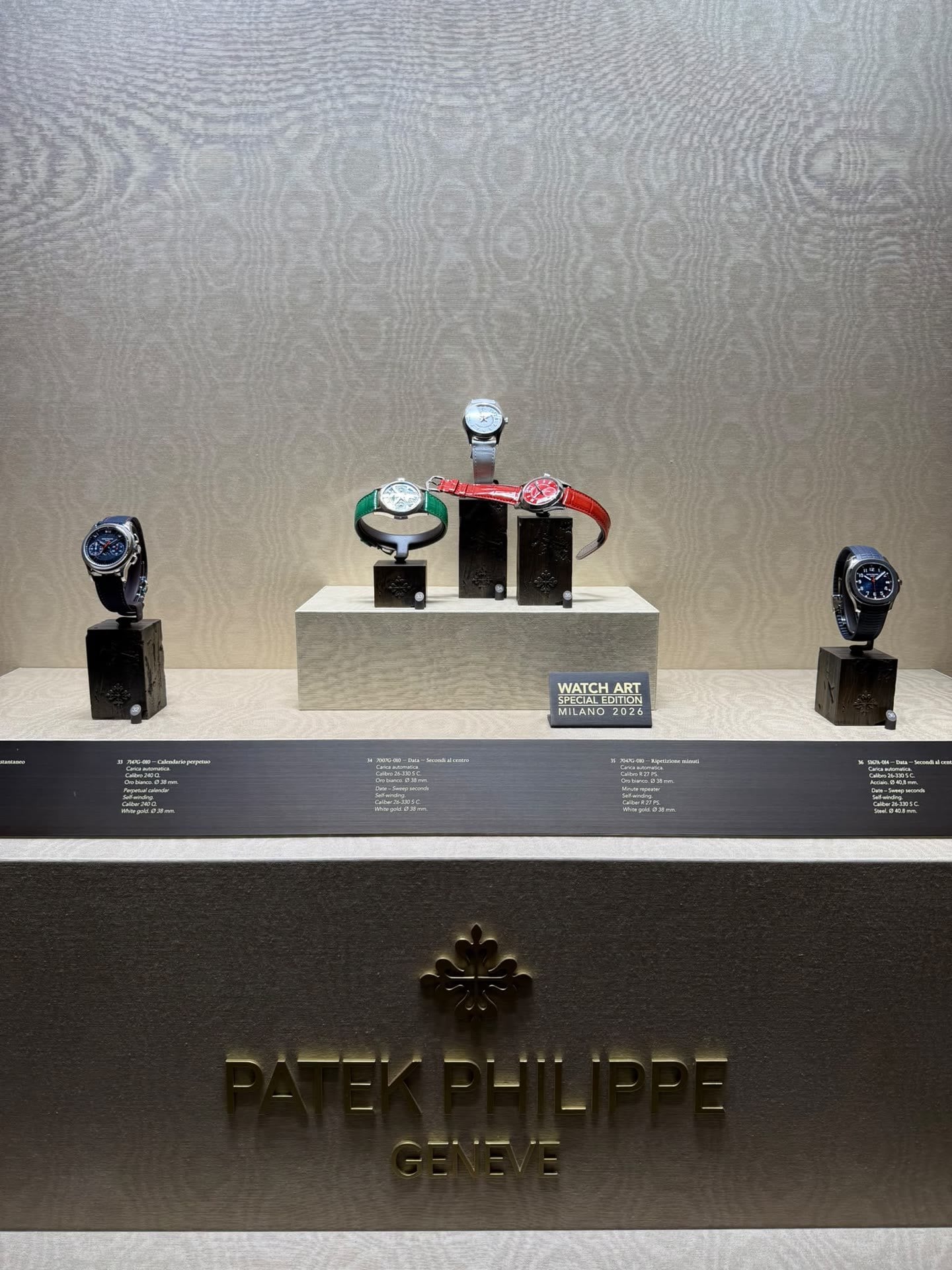 Vitrin på patek philippes utställning i milano med 7147g, 7007g och 7047g på socklar samt aquanaut 5167a och skylten watch art special edition milano 2026 vitrin på patek philippes utställning i milano med 7147g, 7007g och 7047g på socklar samt aquanaut 5167a och skylten watch art special edition milano 2026